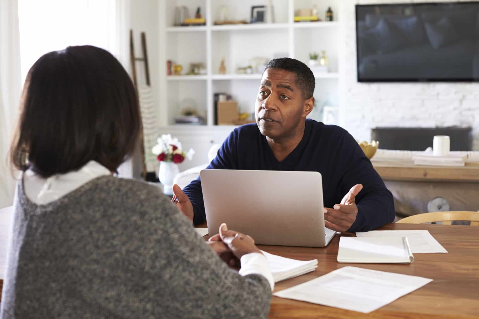 Millennial man with laptop computer giving financial advice to a woman