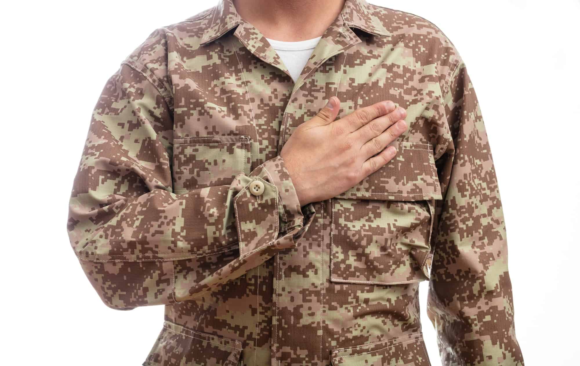 Young soldier with hand on heart standing on white background