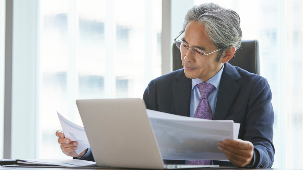 Ejecutivo senior de RR.HH. revisa documentos en su escritorio, centrándose en las prioridades del CHRO en la planificación estratégica de RR.HH. y el liderazgo organizacional.