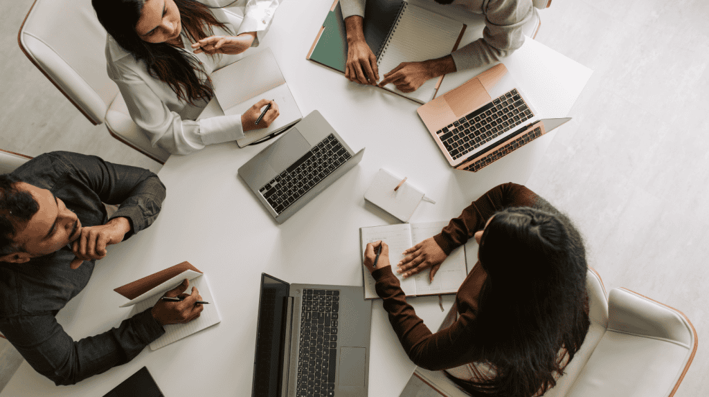 HR team collaborating with laptops and notebooks, discussing AI in HR digital transformation, HR automation, and technology integration.