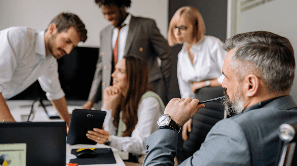 Executive search consultants and senior leaders reviewing candidate profiles and performance data during a C-suite hiring strategy meeting.