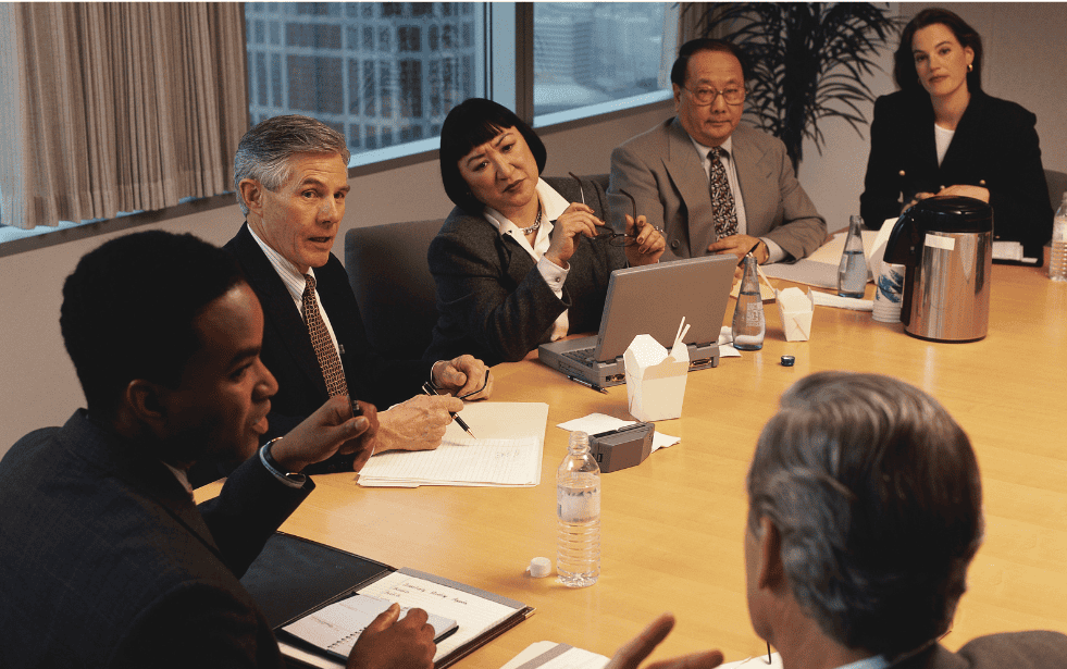 A group of professionals sit around a conference table reviewing financial documents and discussing accounting and finance strategy.