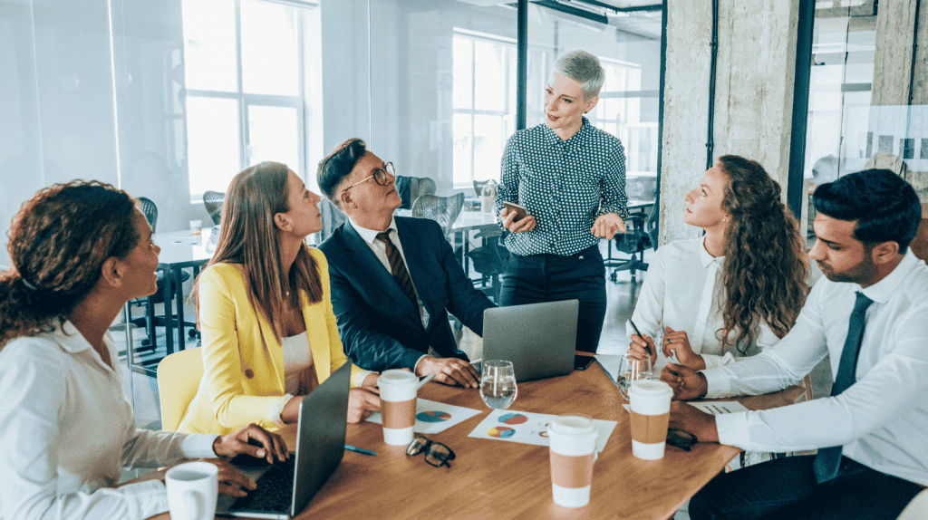 Diverse executive leadership team meets to evaluate culture fit and culture add during a hiring discussion.