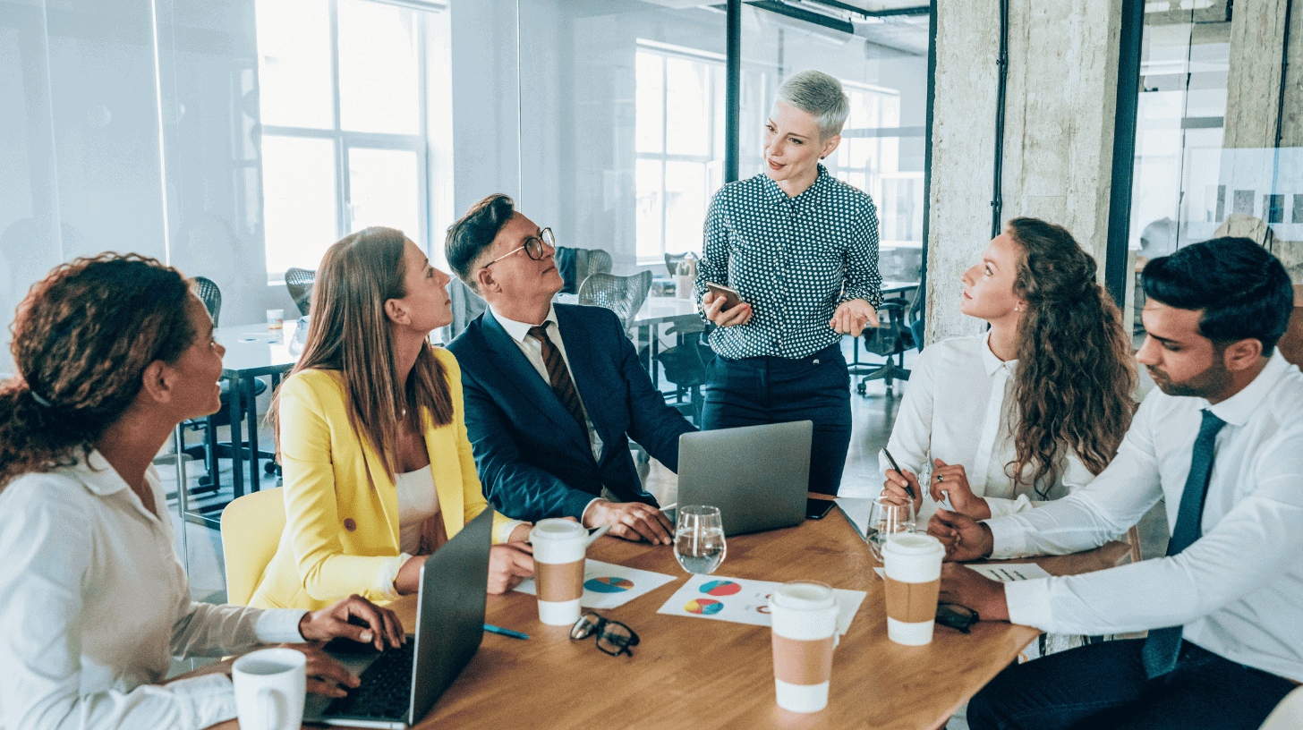Diverse executive leadership team meets to evaluate culture fit and culture add during a hiring discussion.