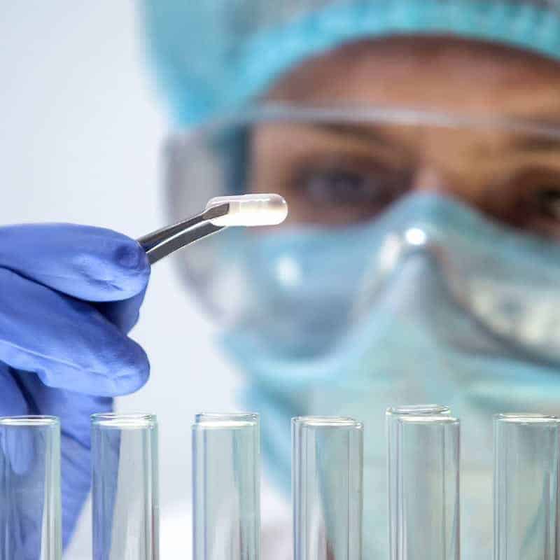 Een onderzoeker met handschoenen plaatst een preparaat onder een microscoop in een biowetenschappelijk laboratorium, ter ondersteuning van recruiters in de biowetenschappelijke sector.
