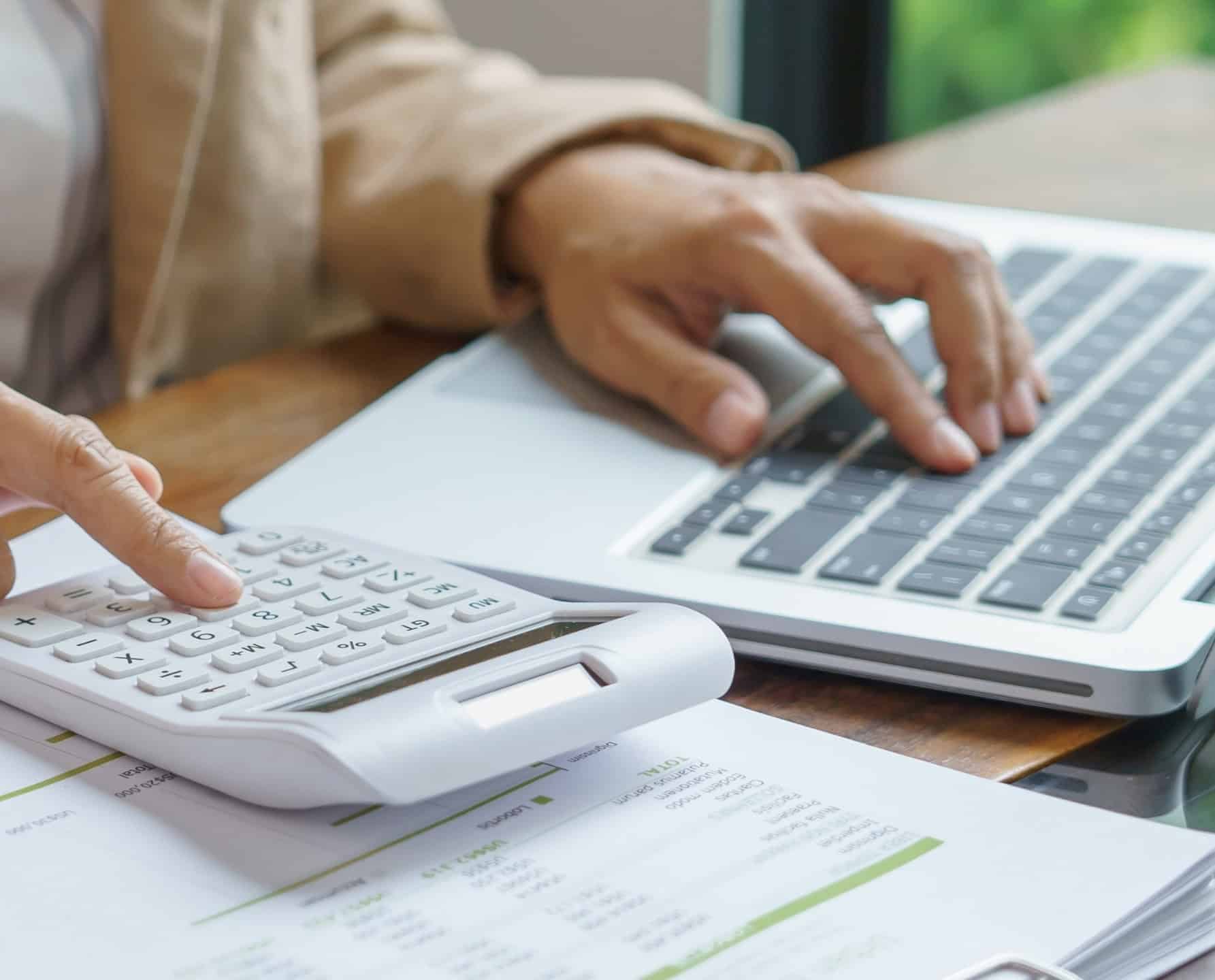 Een accountant die in de accountancysector werkt met een rekenmachine, laptop en financiële rapporten.