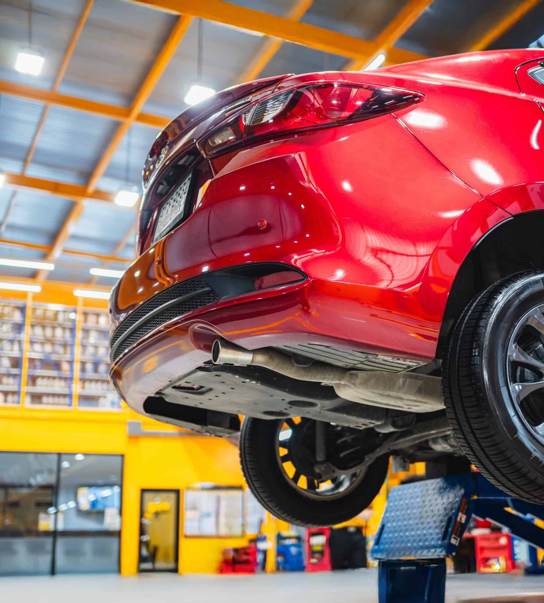 Een rode auto staat op een hydraulische hefbrug in een servicewerkplaats in de auto-industrie.