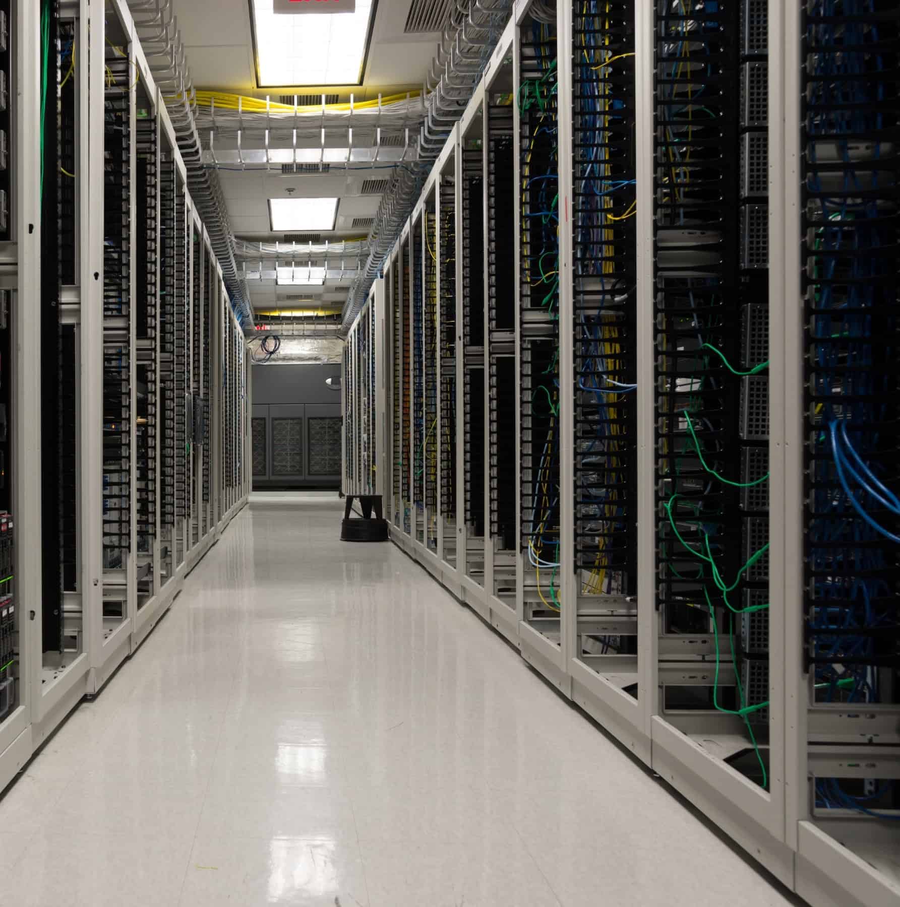 Data center corridor with server racks and network cabling in the cloud infrastructure industry.