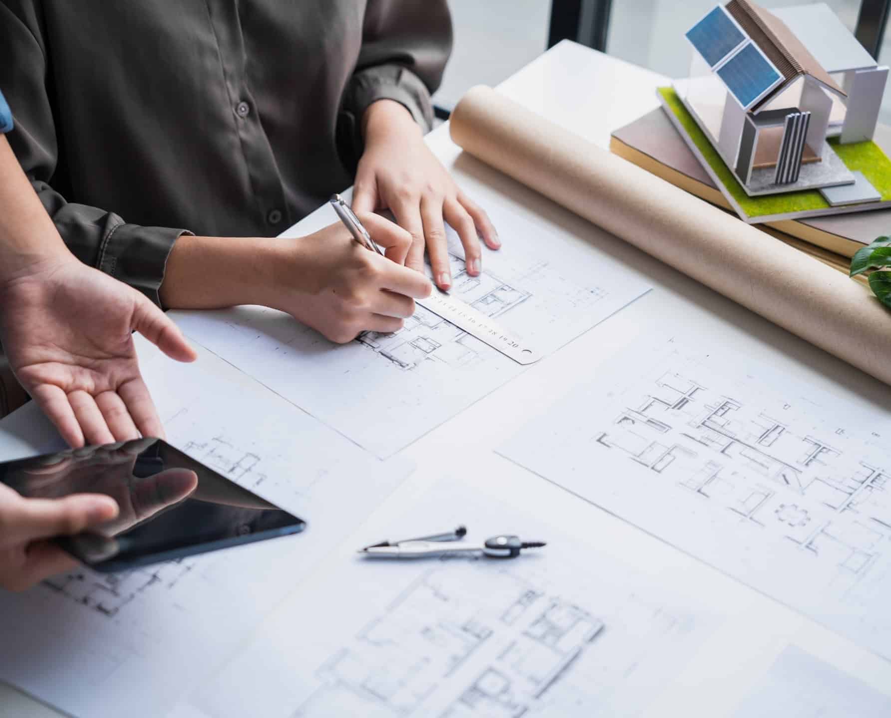 Architecten die plattegronden beoordelen met behulp van tekenprogramma's en een bouwmodel in de ingenieurs- en architectuursector.