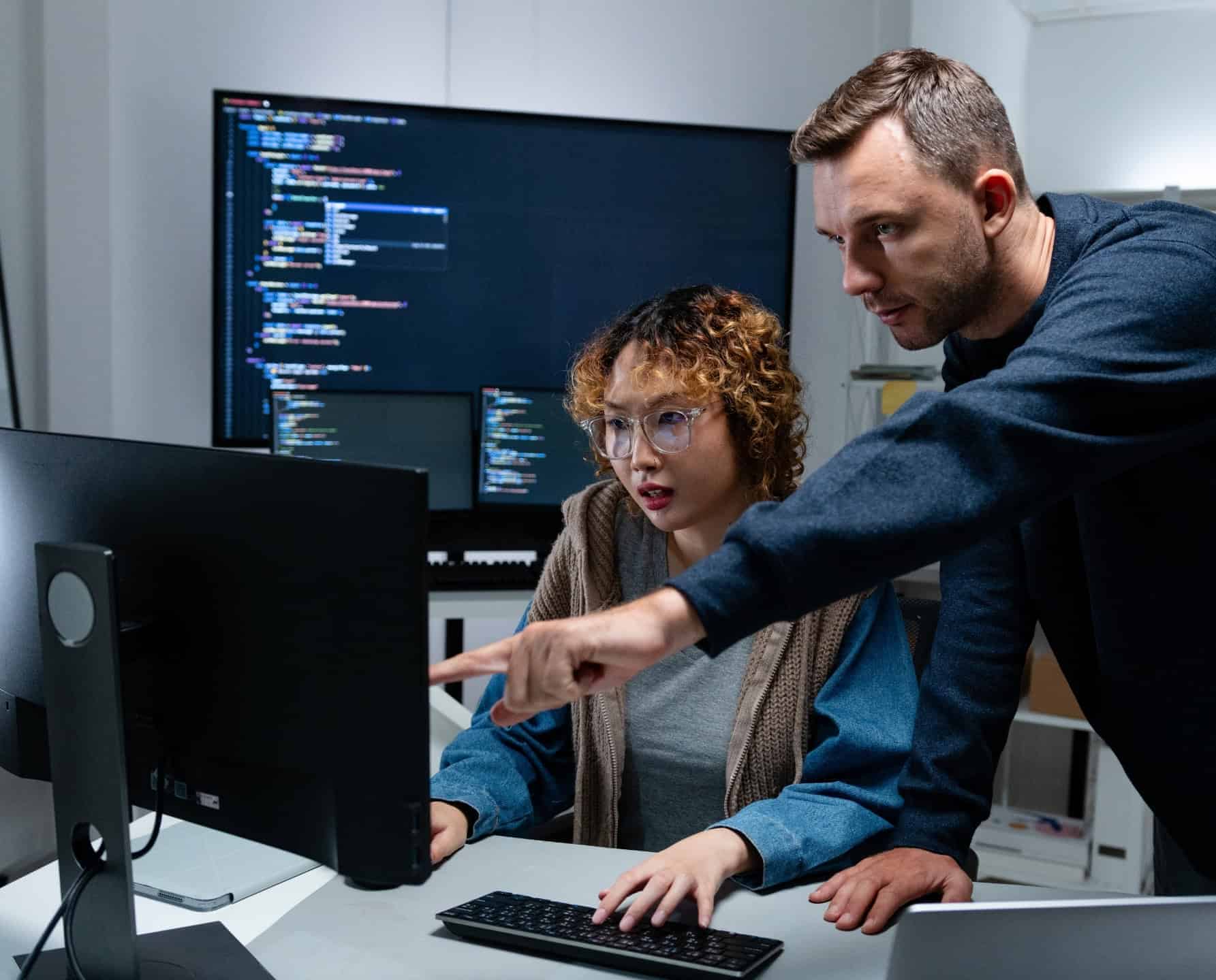 Twee IT-professionals werken samen aan een werkstation met code op het scherm in de IT-dienstverleningssector.