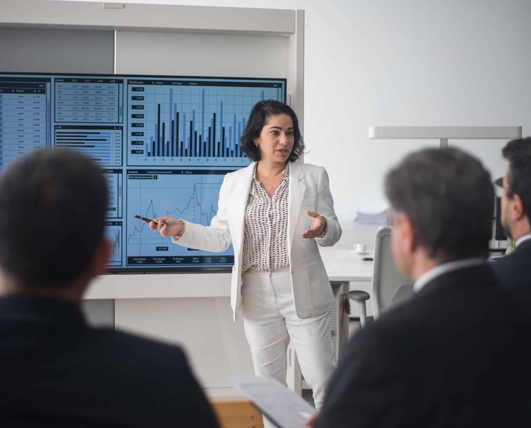 Bedrijfsanalist in de informatiesector die marktgegevens en analysedashboards presenteert aan een directiepubliek.