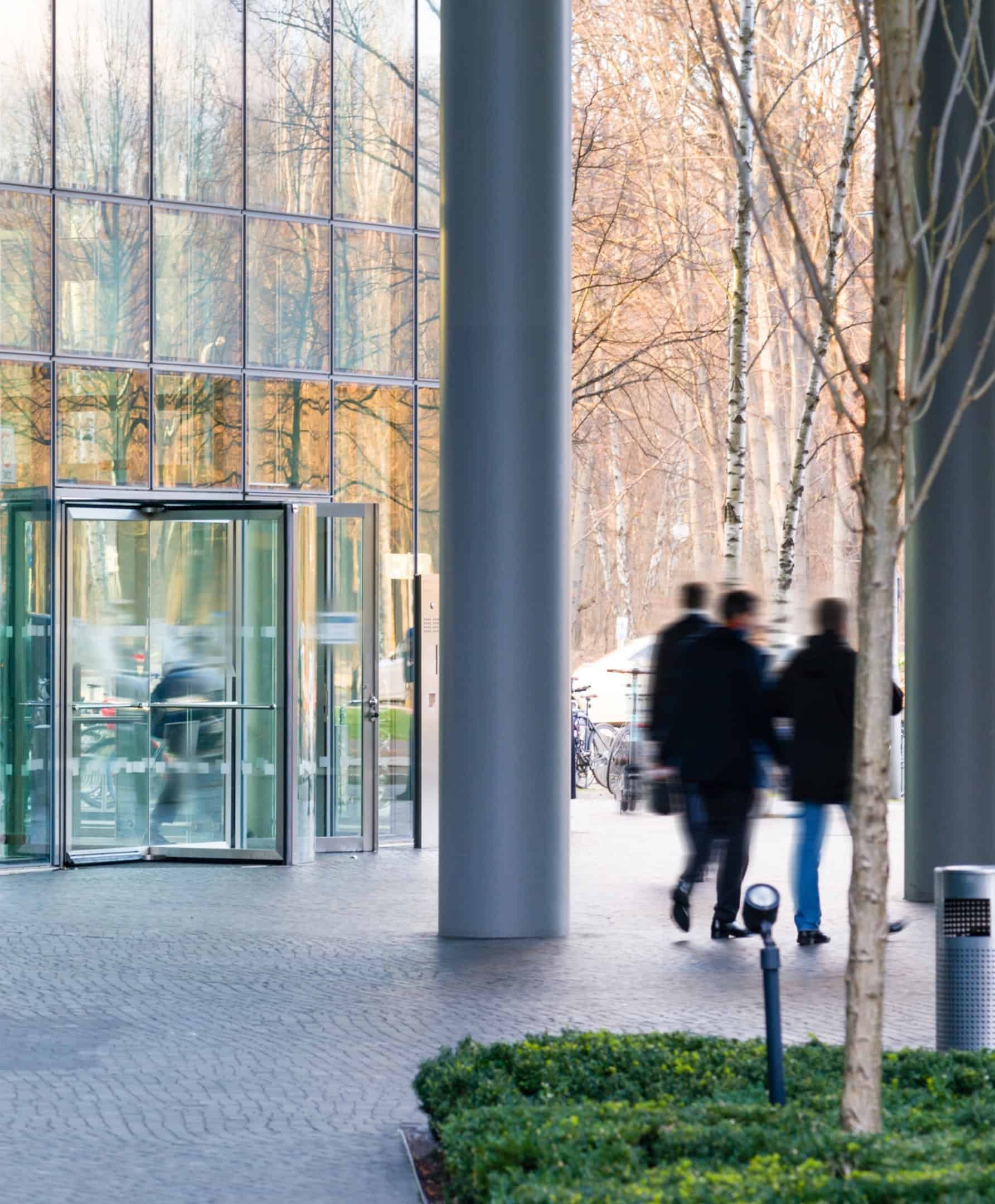 Ejecutivos de crédito privado entrando en un moderno edificio de oficinas acristalado.
