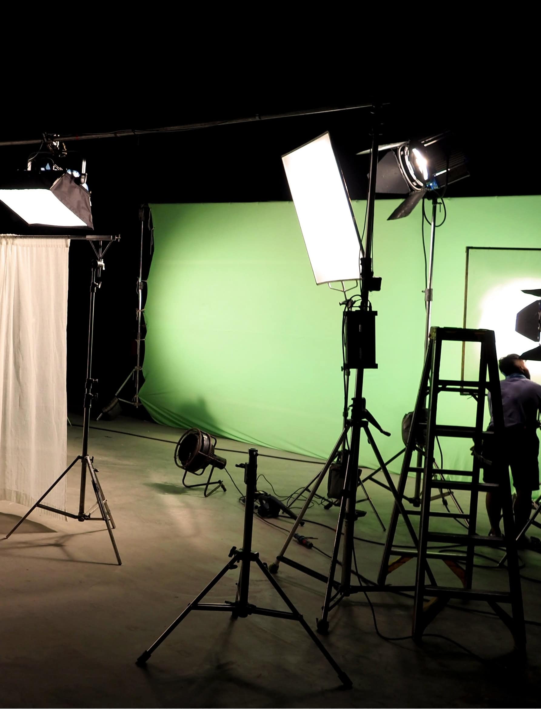 Film production studio with professional lighting rigs and a green screen in media and entertainment.