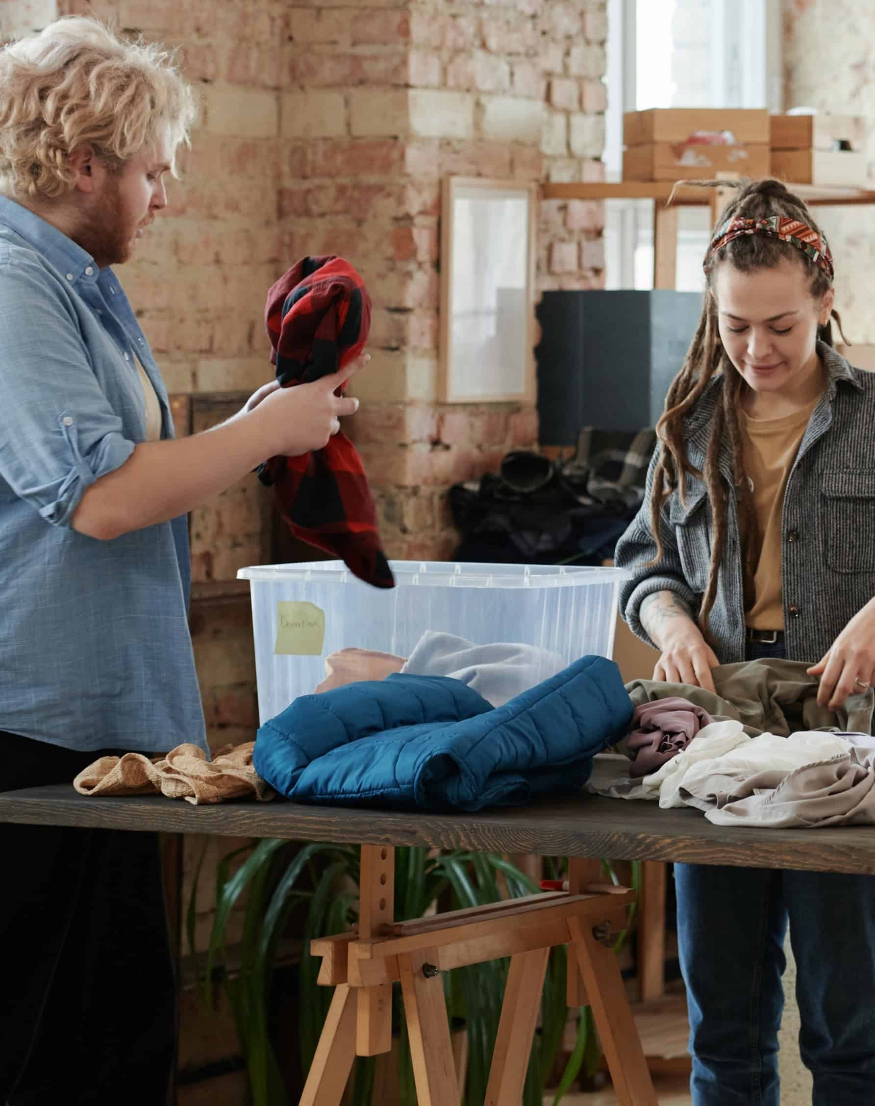 Two volunteers sorting clothing donations at a nonprofit community service organization.