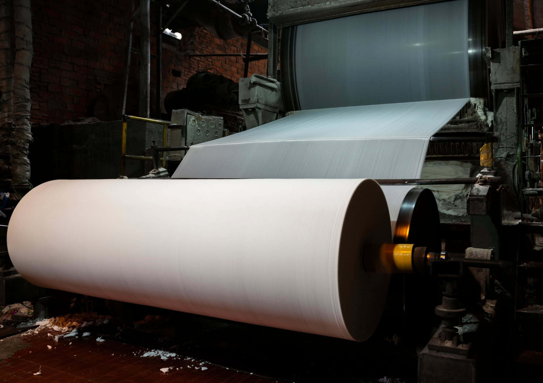 Large paper roll winding on an industrial paper machine inside a pulp and paper mill.