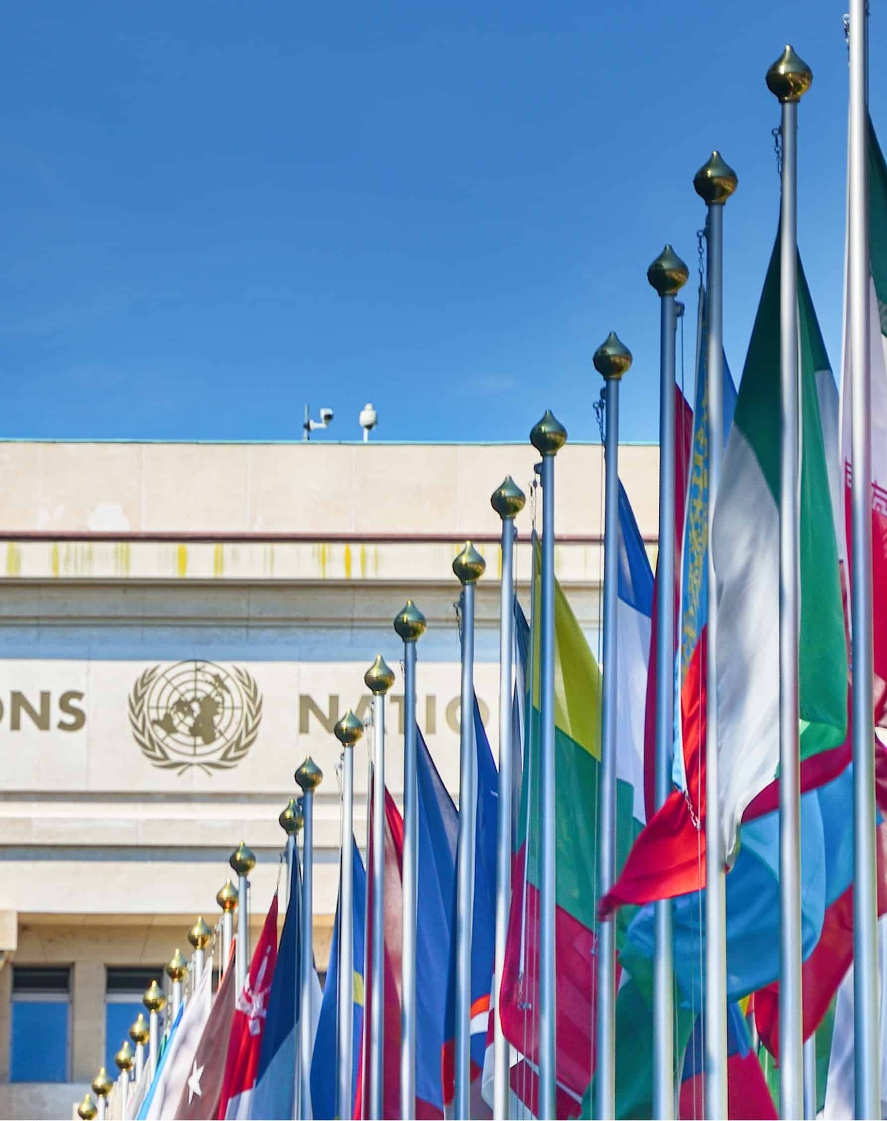 Rows of international flags flying outside a multilateral organization's headquarters.