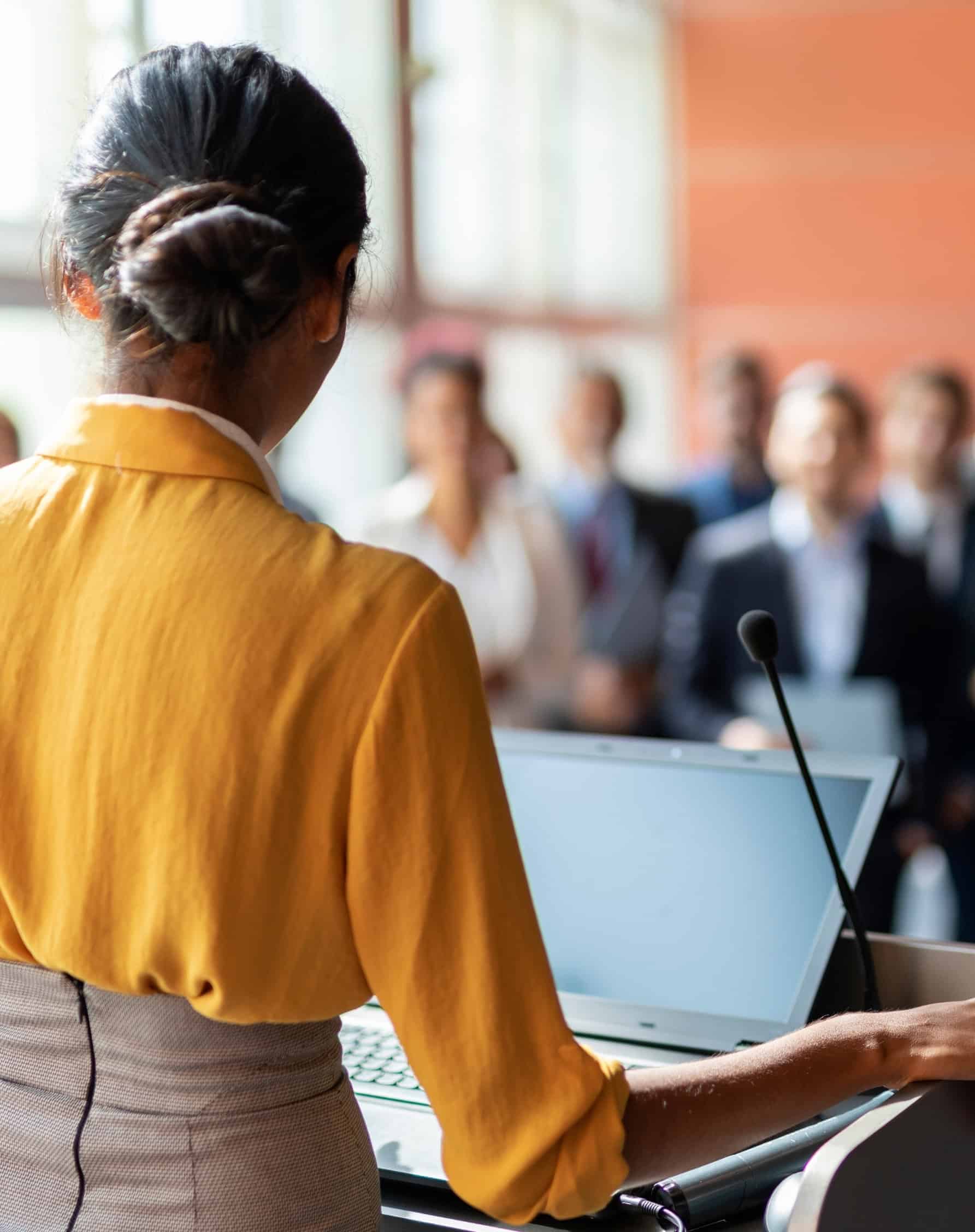A think tank executive presenting findings to an audience at a public policy forum.