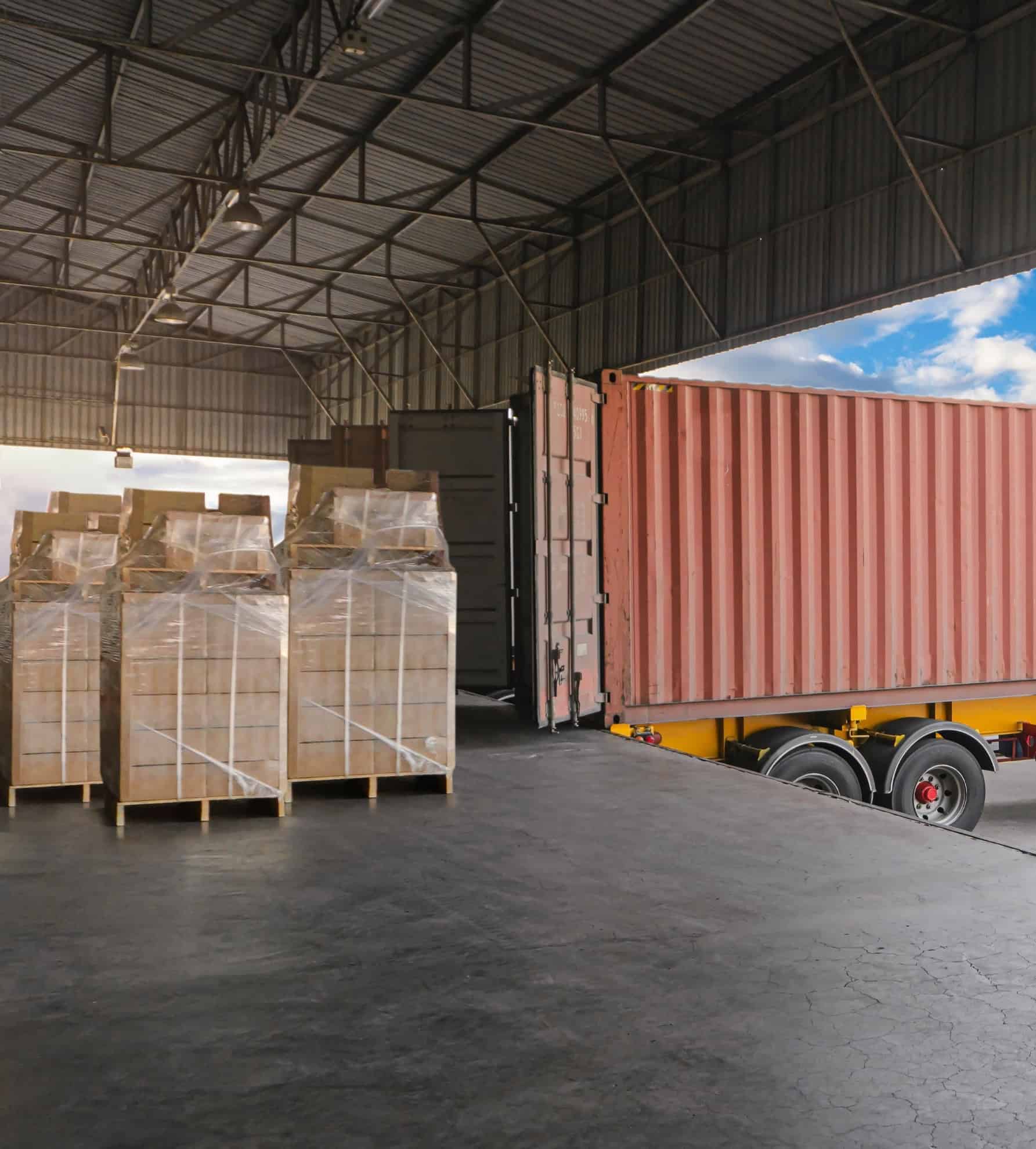 Gepalletiseerde vracht wordt in een containerwagen geladen bij een laadperron in de logistieke sector.