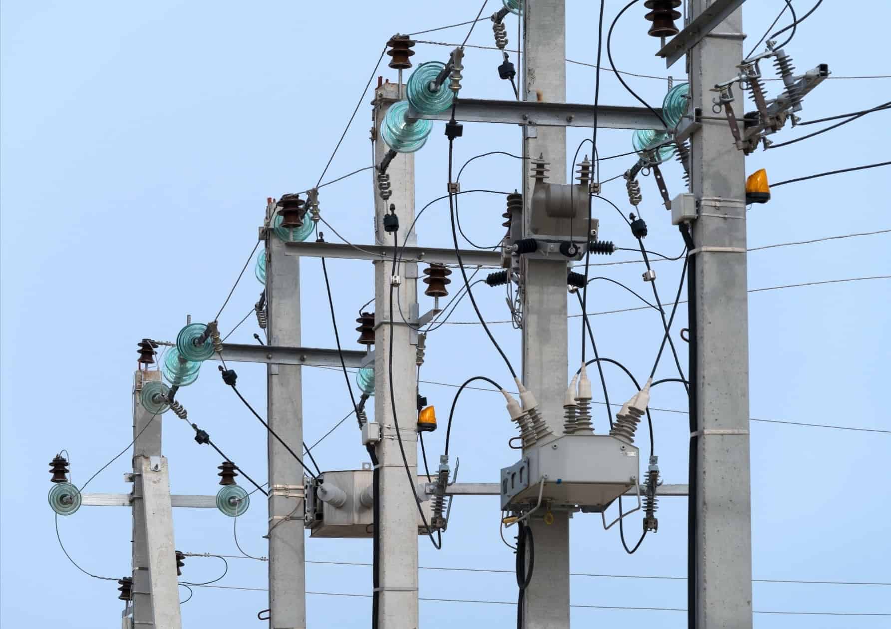 Electrical transmission poles with glass insulators and distribution transformers in the utilities industry.