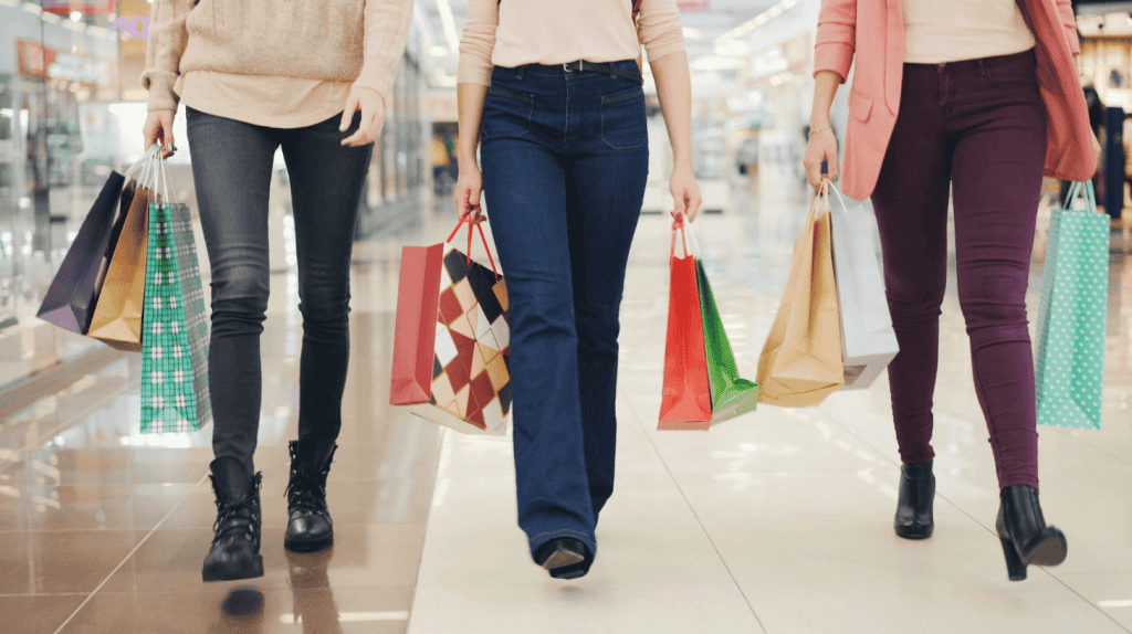 Shoppers carrying bags through a retail mall, representing the consumer brands served by executive search firms.