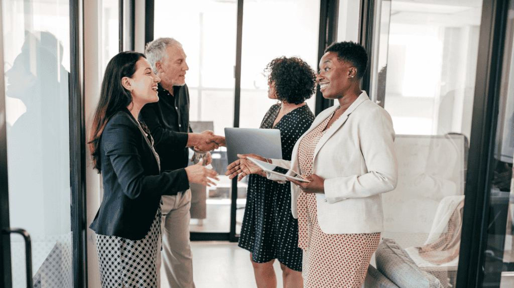 Two women shake hands in a glass-walled office as they finish up the interview portion of the executive search process.