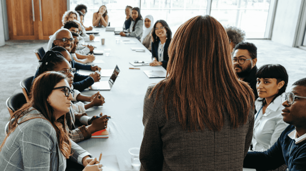Executive addressing a diverse team in a boardroom meeting, embodying key leadership traits.