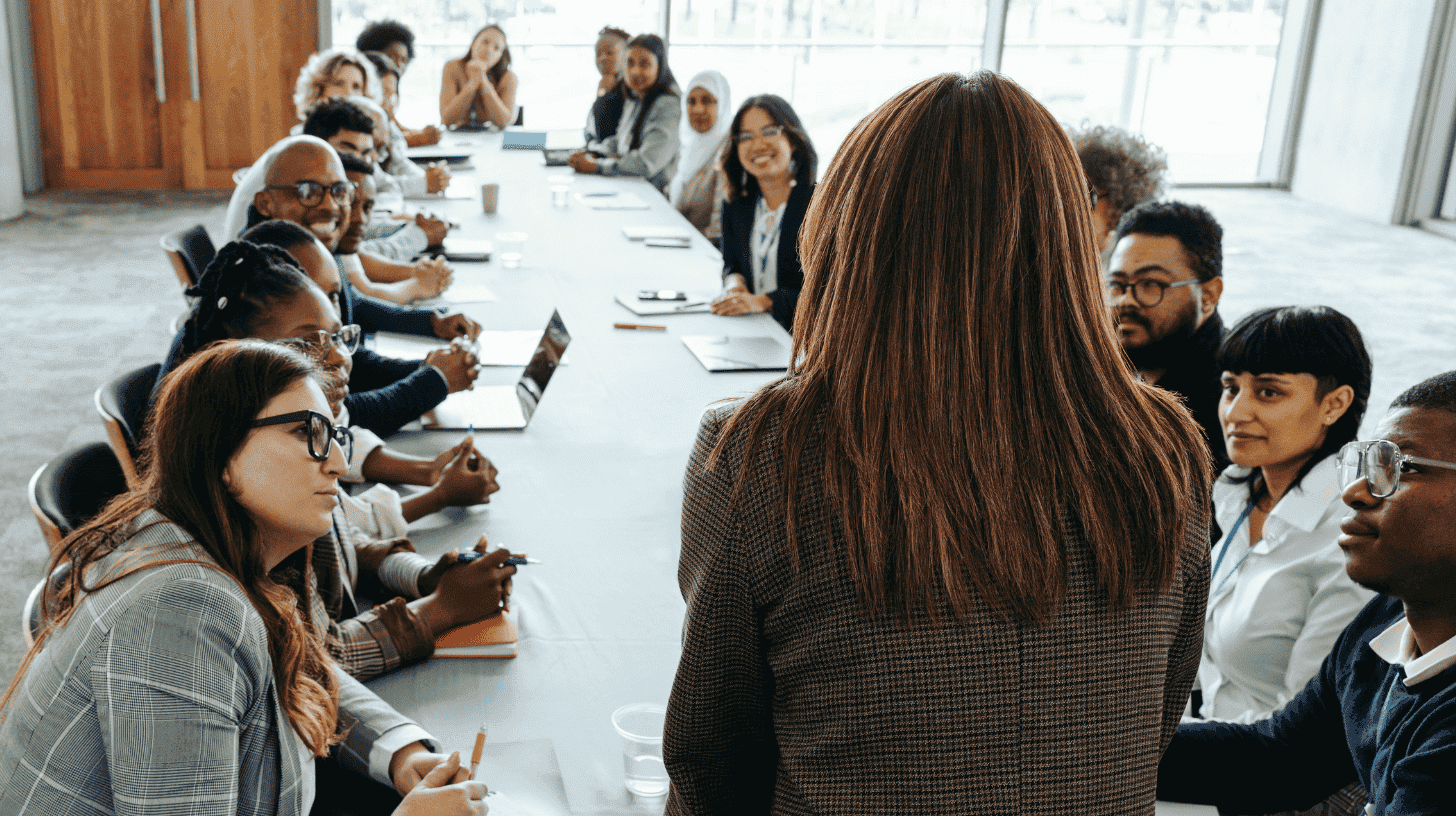 Executive addressing a diverse team in a boardroom meeting, embodying key leadership traits.